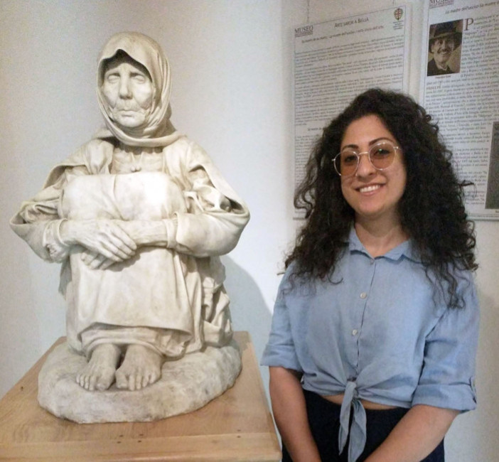 La guida turistica Maria Grazia Hussain Tedde accanto alla scultura "La Madre dell'ucciso" di Francesco Ciusa, unica versione marmorea firmata dall'artista, custodita presso il Museo delle Migrazioni, Cammini e Storie di Popoli di Pettinengo. La guida turistica Maria Grazia Hussain Tedde accanto alla scultura "La Madre dell'ucciso" di Francesco Ciusa, unica versione marmorea firmata dall'artista, custodita presso il Museo delle Migrazioni, Cammini e Storie di Popoli di Pettinengo.